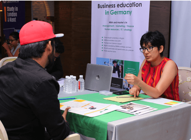 A counsellor and a team member are attending three students at an exhibition.